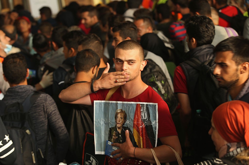 A migrant from Syria holds a picture of German Chancellor Angela Merkel as he and approximately 800 others arrive from Hungary at Munich Hauptbahnhof main railway station on September 5, 2015 in Munich, Germany. Thousands of migrants are traveling to Germany following an arduous ordeal in Hungary that resulted in thousands walking on foot and then being bussed by Hungarian authorities from Budapest to the Austrian-Hungarian border.